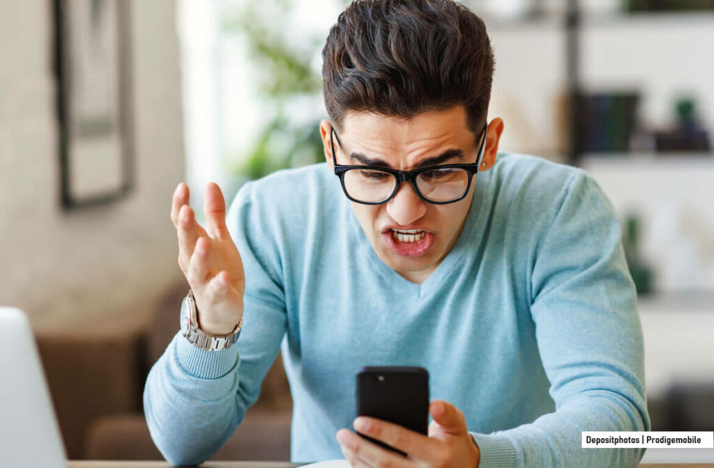 Homme frustré tenant son iPhone après avoir reçu un appel indésirable