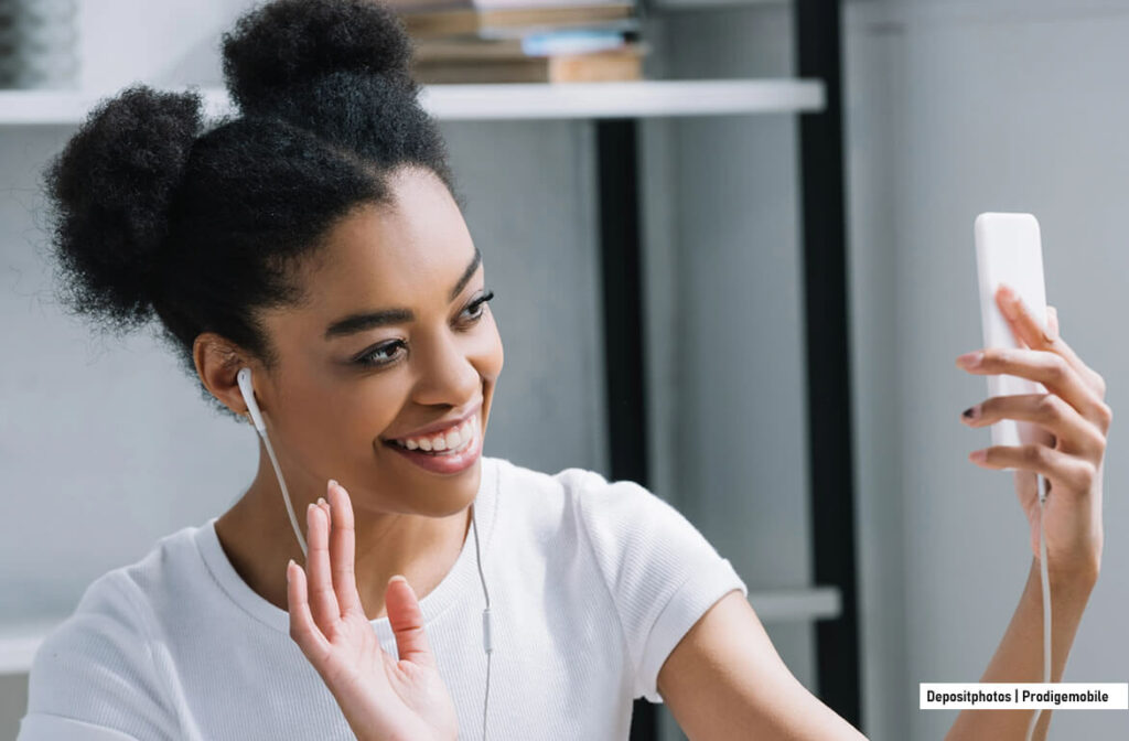 Comment passer un appel visio depuis un smartphone Android Jeune femme passant un appel vidéo à l’aide de son smartphone et d’écouteurs