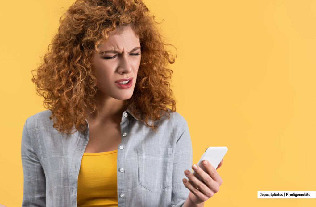 Bloquer les SMS indésirables sur un téléphone Android Une femme prenant connaissance d’un SMS indésirable sur son smartphone Android