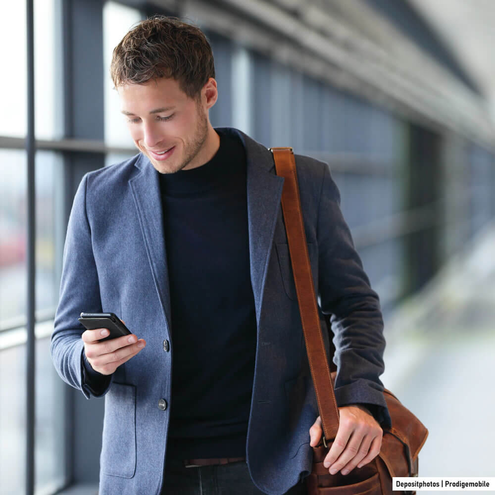 Homme d’affaires utilisant son smartphone dans un aéroport avec un forfait mobile